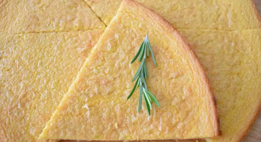 Schiacciata pokrojona w trójkąty, ozdobiona gałązką rozmarynu.