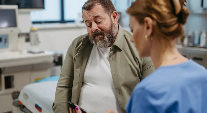 Lekarz pokazuje pacjentowi glukometr w gabinecie lekarskim.