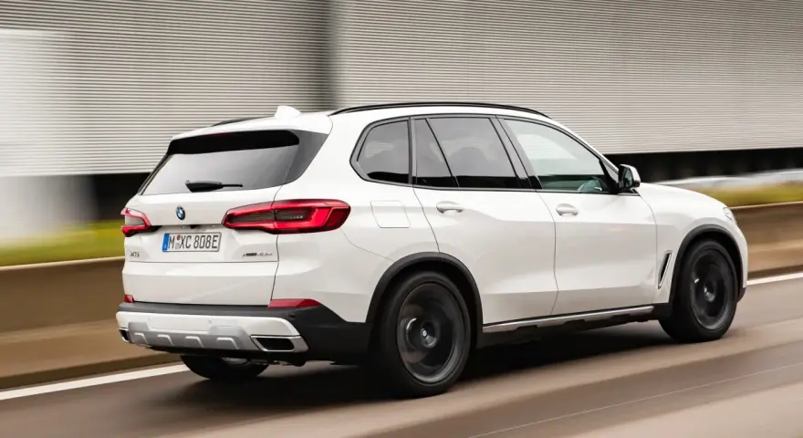 Białe BMW X5 M50d pędzi po autostradzie, zostawiając za sobą rozmyte tło.