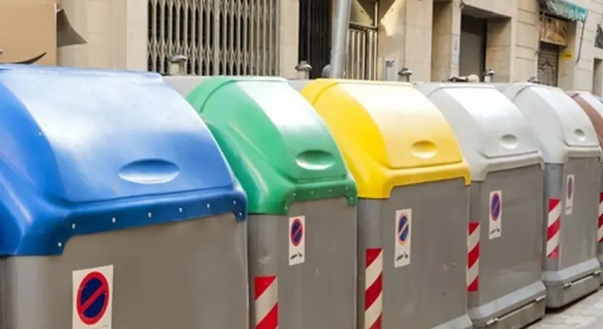 Fila de contenedores de reciclaje de Ecoembes en la calle: azul, verde, amarillo y grises.