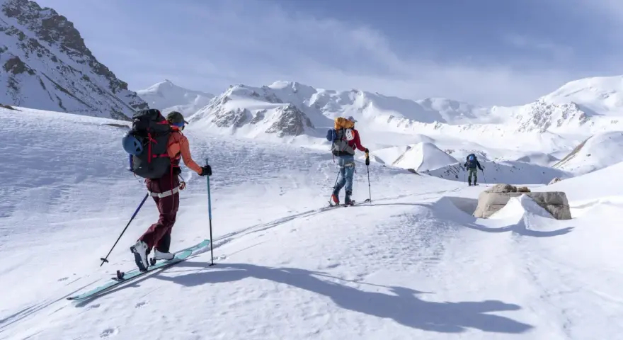 Trois skieurs s'aventurent dans un paysage montagneux enneigé. Une photo ski montagne qui capture l'immensité et la beauté de la nature.