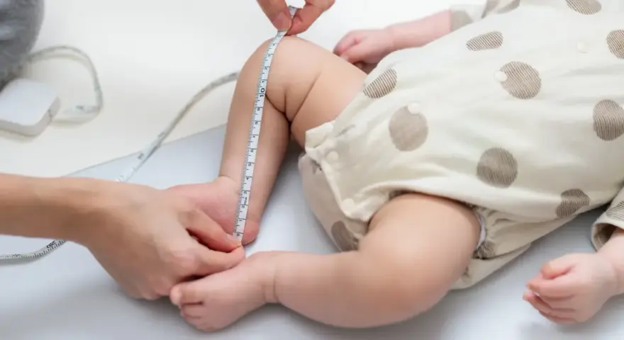 Dziecko w body w kropki, mierzone centymetrem. Sprawdzanie, jaki to rozmiar dla malucha do 3 miesięcy.