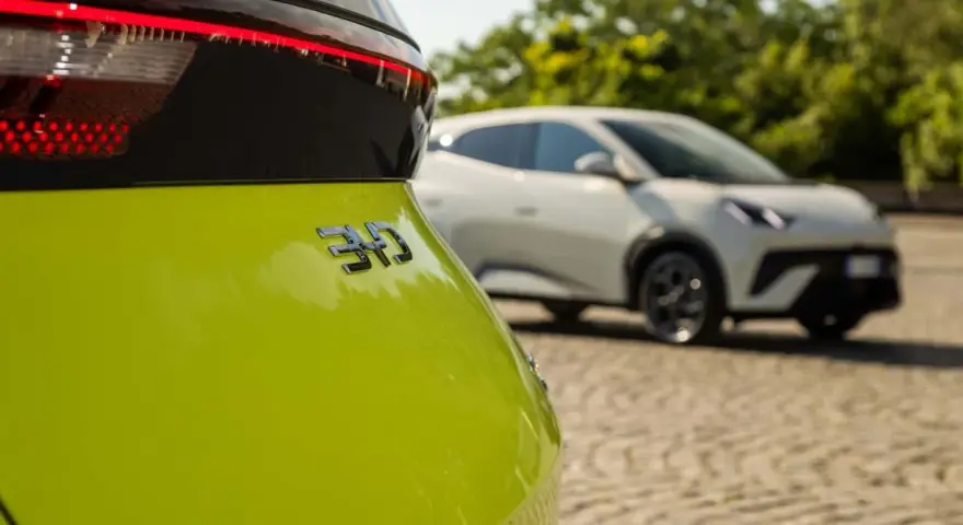 Jasnozielony samochód elektryczny BYD z napisem "310" na klapie bagażnika, w tle biały samochód.