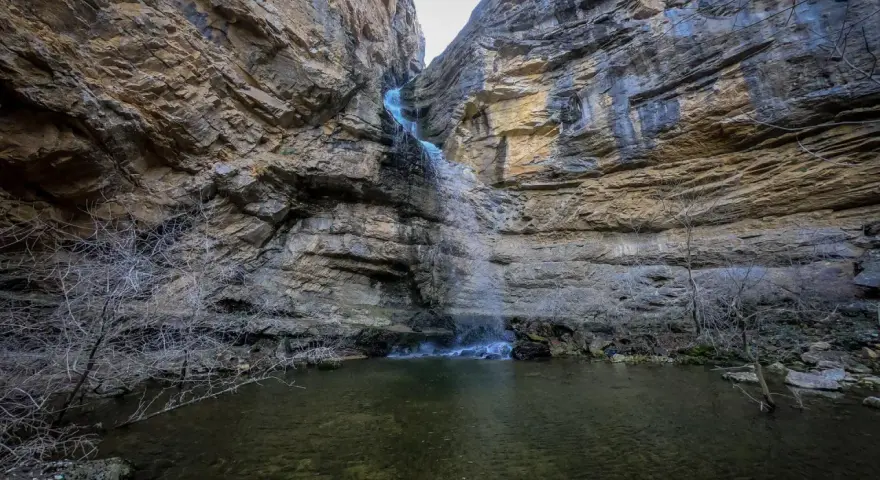 Cascadas en Guadalajara, un estrecho cañón rocoso con una cascada cayendo en una poza de agua clara.