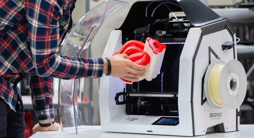 Inżynier wyjmuje z drukarki 3D skomplikowany element, pokazując potencjał druku 3D w przemyśle.
