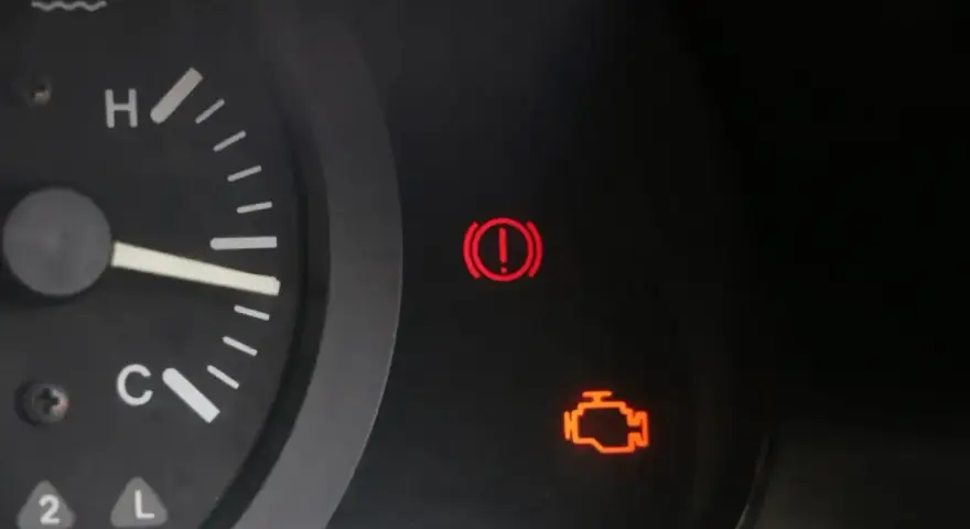 Kontrolka silnika świeci się, wskazując błąd DTC P0010 w Renault. Obok świeci się kontrolka hamulca ręcznego.