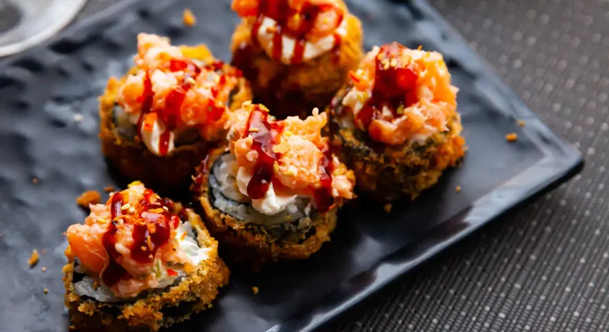 Pięć kawałków sushi w tempurze z łososiem i sosem, idealne na przekąskę.