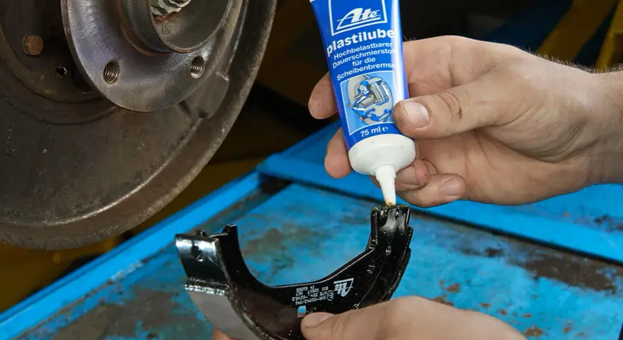 Mechanik nakłada smar ATE Plastilube na szczęki hamulcowe. To właściwy smar do tłoczków hamulcowych, zapewniający płynne działanie układu.