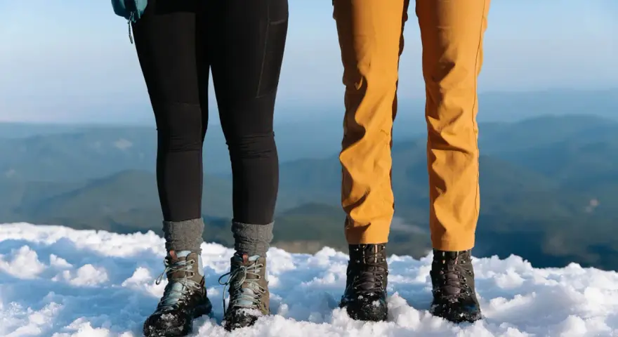 Dwie pary solidnych butów trekkingowych, niczym nowoczesne walonki, stoją na śniegu.