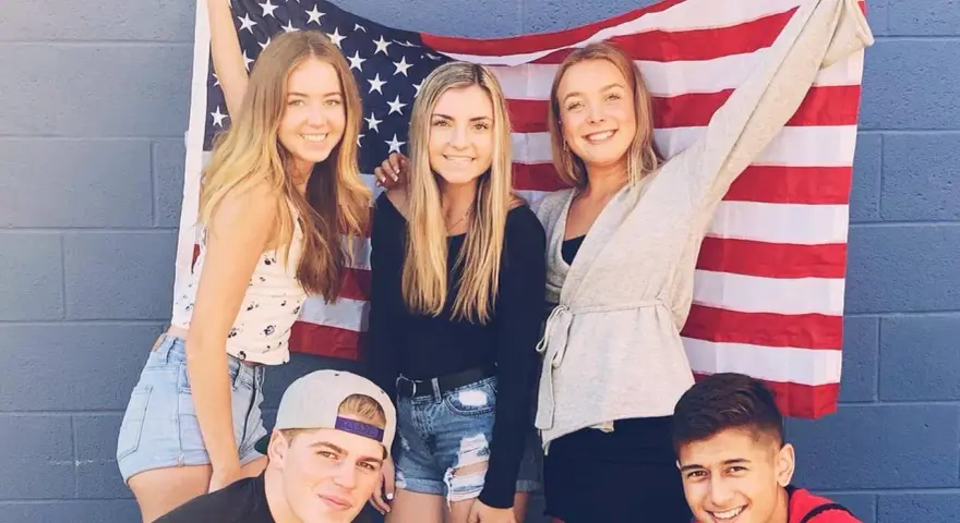 Freunde feiern ihr High School Jahr in den USA vor einer amerikanischen Flagge.