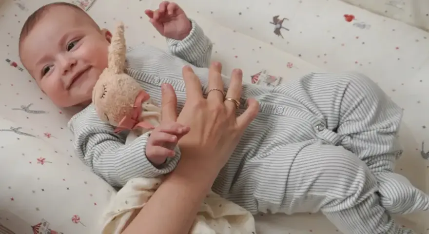 Uroczy niemowlak w pajacyku leży w łóżeczku. Dowiecie się, jak ubrac dziecko do spania, by było mu wygodnie.