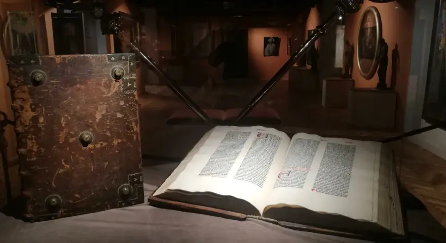 W muzeum diecezjalnym w Pelplinie eksponaty takie jak stary, oprawny księgozbiór i otwarta księga z tekstem przyciągają wzrok zwiedzających.