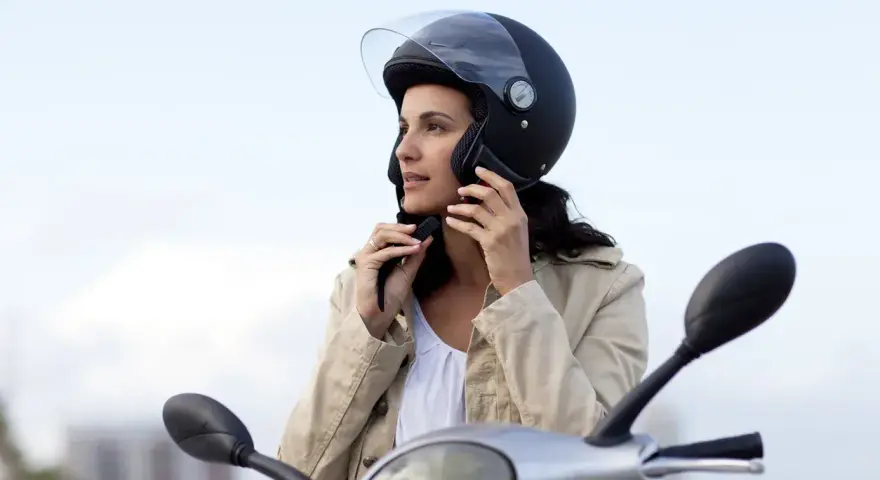 Donna con casco da moto nero, pronta a partire. Non è un luogo dove si buttano i caschi da moto, ma un simbolo di sicurezza.