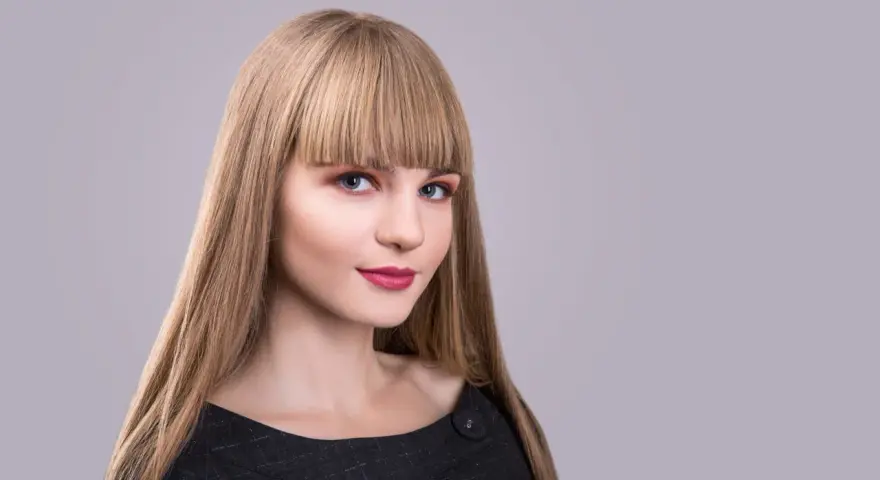 Blondynka z prostą grzywką, która podkreśla jej niebieskie oczy. Różne rodzaje grzywek mogą całkowicie odmienić wygląd.