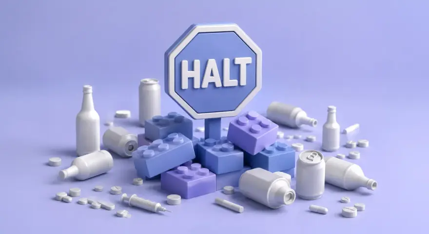 Symbol "HALT" otoczony klockami i przedmiotami kojarzonymi z nałogami, jak butelki, puszki, tabletki i strzykawka. Program halt przykłady.