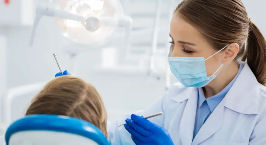 Dentystka bada uśmiech dziecka, by wykluczyć zapalenie dziąseł.