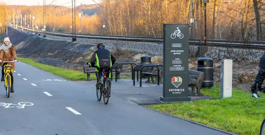 Rowerzyści na ścieżce wzdłuż torów kolejowych. Nowe trasy rowerowe Śląsk zachęcają do aktywnego spędzania czasu.