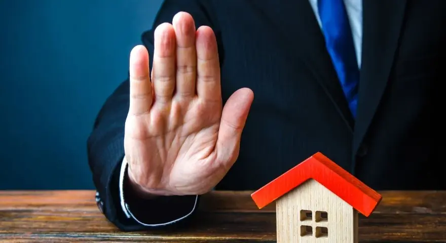 Main tendue, un homme en costume bloque une petite maison. Mon ex refuse la désolidarisation, le bien reste bloqué.