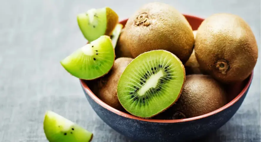 Miseczka pełna kiwi, jedno przekrojone na pół, pokazuje soczysty miąższ. Czy można jeść kiwi ze skórką? Tak, jest jadalna i pełna witamin!