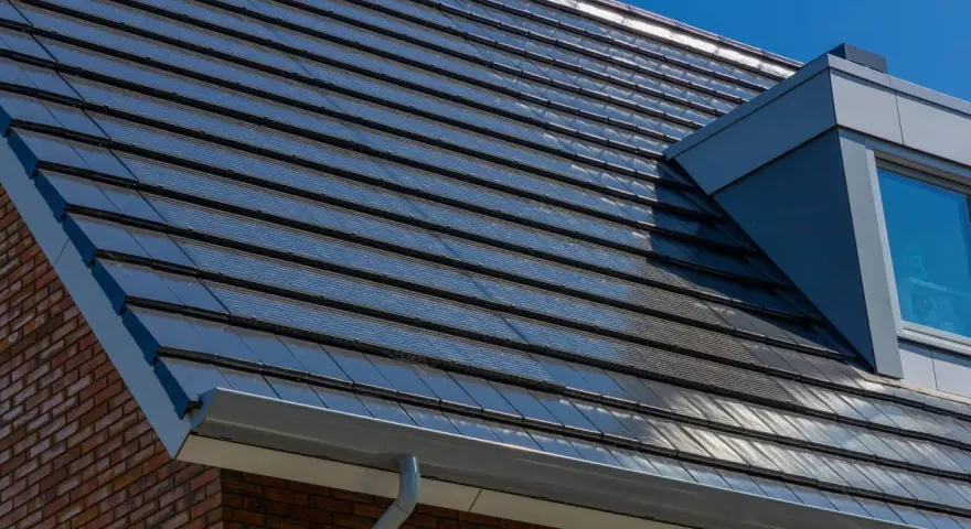 Nowoczesny dach z ciemną dachówką fotowoltaiczną, która dyskretnie integruje się z architekturą domu, zapewniając czystą energię.