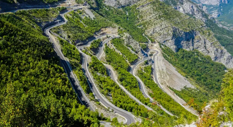 W serpentynach albania trasa pnie się po stromych zboczach gór, otoczona bujną zielenią.