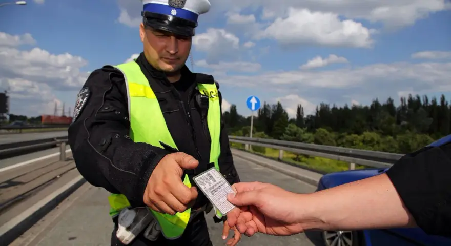 Policjant w kamizelce odblaskowej prosi o okazanie dokumentów. Czy trzeba mieć przy sobie prawo jazdy? Tak, podczas kontroli drogowej.