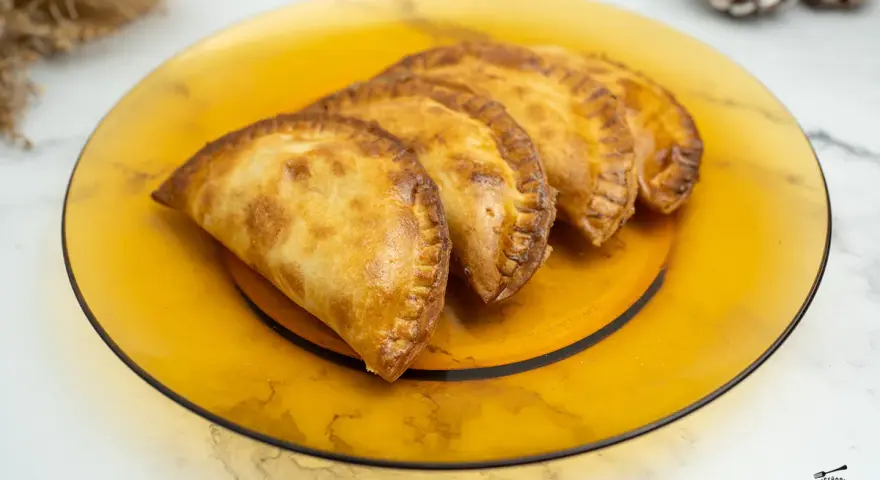 Empanadillas doradas y crujientes, recién hechas en freidora de aire, servidas en plato ámbar.