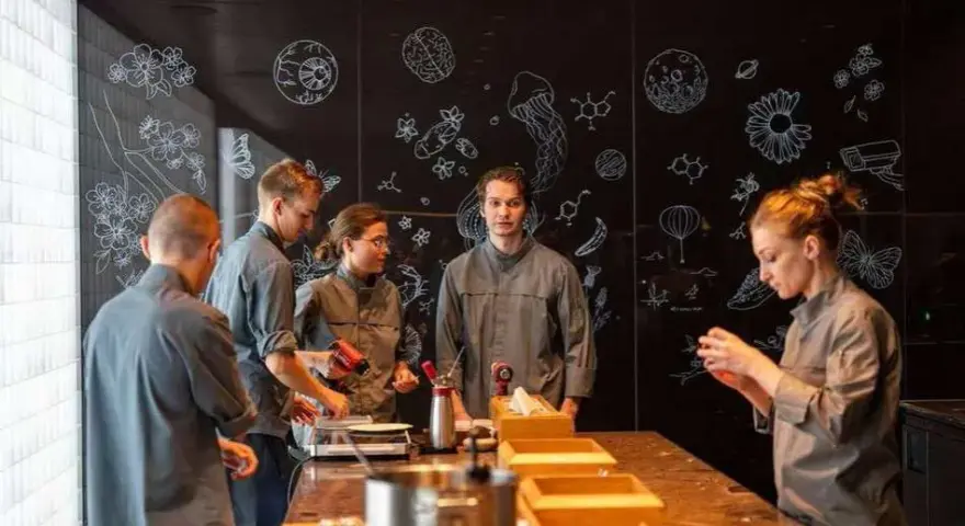 Une série de photos montrant une équipe en cuisine, devant un mur noir décoré de dessins scientifiques et floraux.
