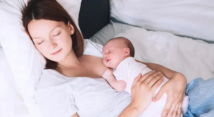 Matka śpi z dzieckiem przy piersi, doświadczając piękna laktacji.
