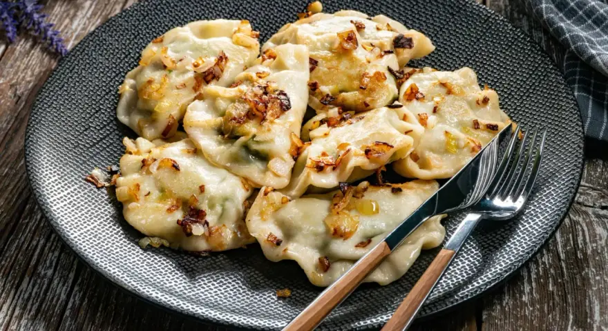 Pyszne pierogi z cebulką na talerzu. Zastanawiasz się, ile gotować pierogi, by były idealne?