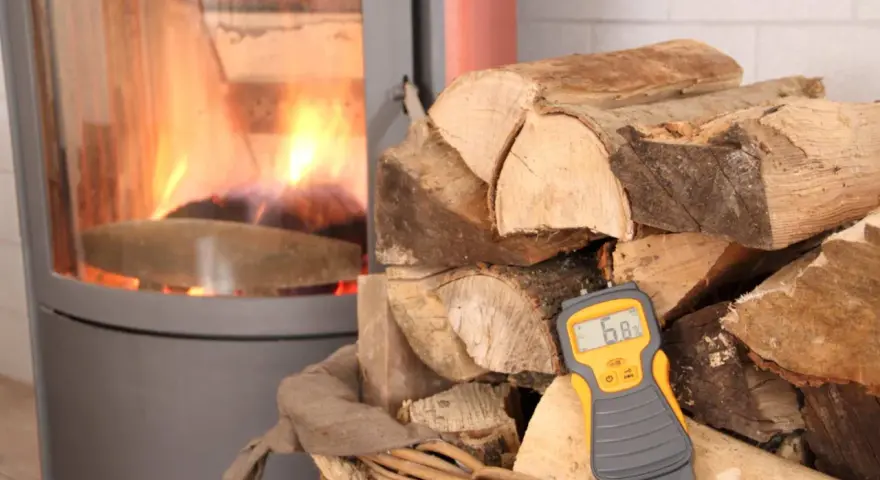 Poêle avec feu, bois de chauffage et humidimètre affichant 6.8%.