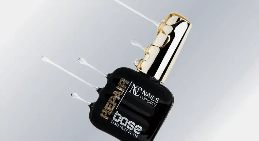 Czarna buteleczka z produktem do paznokci "base" od Nails Company, z płynnym, przezroczystym produktem wypływającym z butelki.