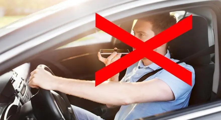 Uomo al volante che usa il cellulare, vietato dall'art. 173 CDS. La croce rossa indica il divieto.