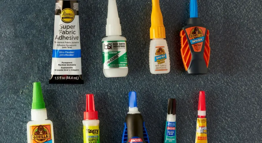 A collection of super glue bottles, including Gorilla Glue and Krazy Glue, are laid out for a comparison of bondic vs super glue.