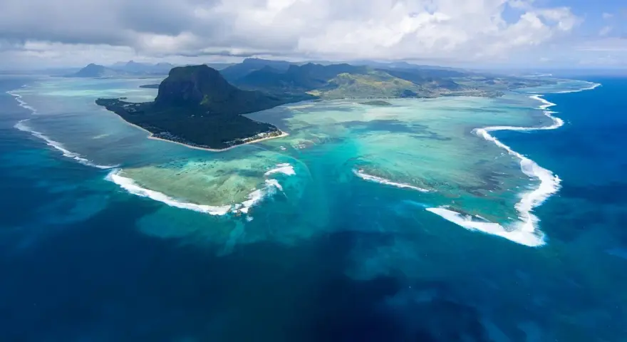 Majestatyczny Le Morne Brabant góruje nad turkusową laguną Mauritiusa. Woda mieni się odcieniami błękitu i zieleni, a białe fale rozbijają się o rafę.