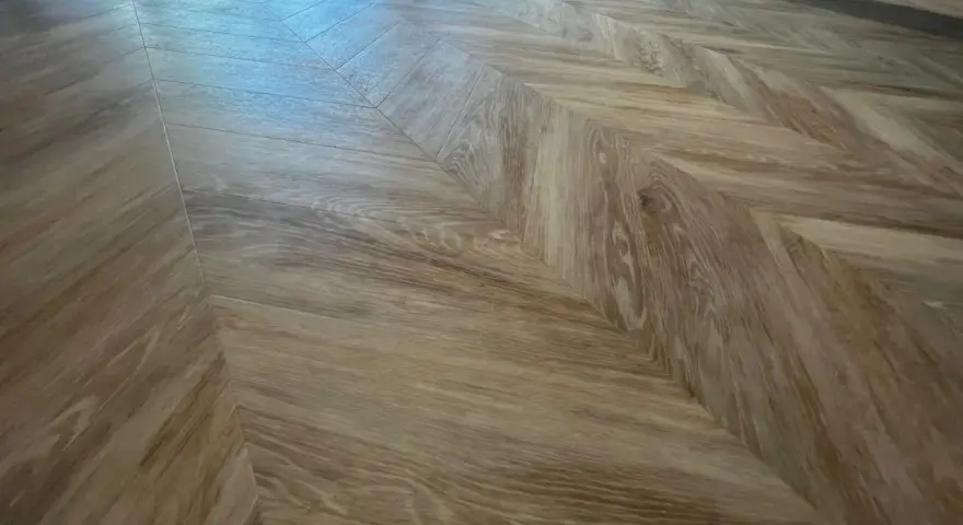 Drewniane panele ułożone we wzór jodełki. Jaki podkład zastosowano pod panele?