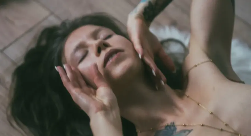 Lilith w lwie, z dłońmi na twarzy, w zmysłowym uścisku.