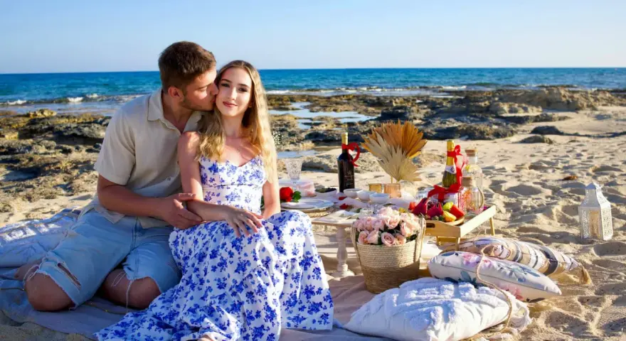 Romantyczny piknik na plaży na Cyprze. Para cieszy się chwilą, a na stole czekają przysmaki. Idealne na wycieczki fakultatywne.