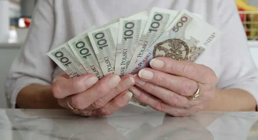 Dłonie trzymające polskie banknoty 100 i 500 zł. Numerologia 8 z dnia urodzenia może symbolizować stabilność finansową.