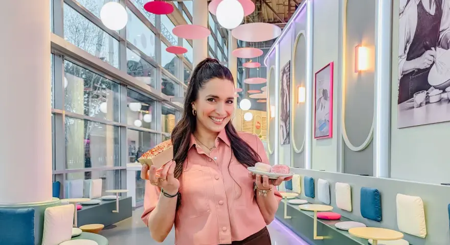 Frau hält süße Leckereien, perfekt zum Europapark Essen mitnehmen. Bunte Deko und gemütliche Sitzgelegenheiten laden zum Verweilen ein.