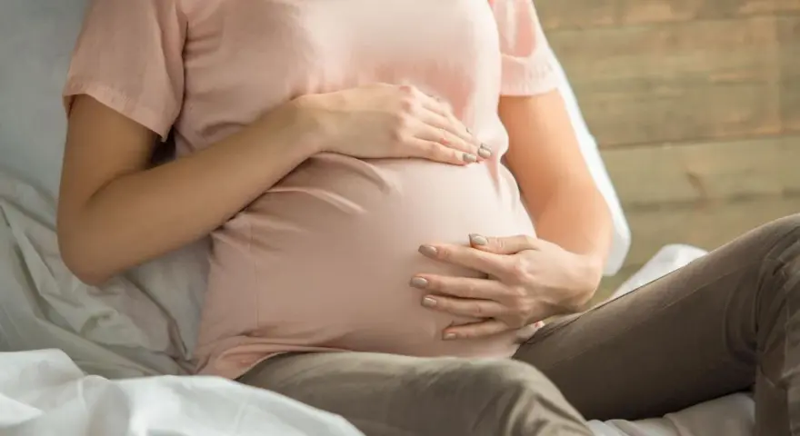 Kobieta w ciąży z dłońmi na brzuchu, martwiąca się o niskie erytrocyty w ciąży.