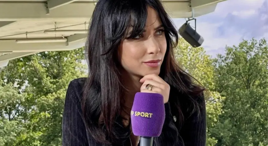 Maja Strzelczyk, dziennikarka sportowa, z mikrofonem Polsat Sport. W tle zielone drzewa i niebo.