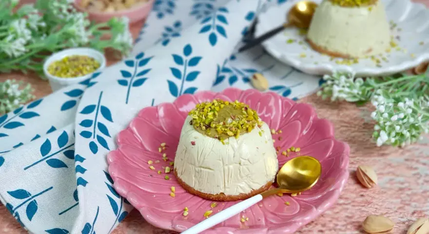 Delizioso semifreddo al pistacchio, guarnito con crema e granella di pistacchi, servito su un piatto rosa.