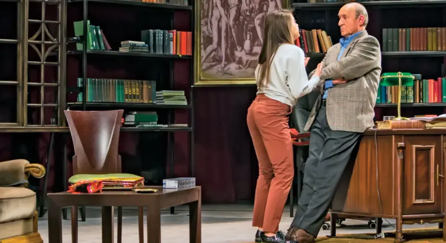 Młoda kobieta rozmawia ze starszym mężczyzną w gabinecie pełnym książek. Scena z przedstawienia "Edukacja Rity".