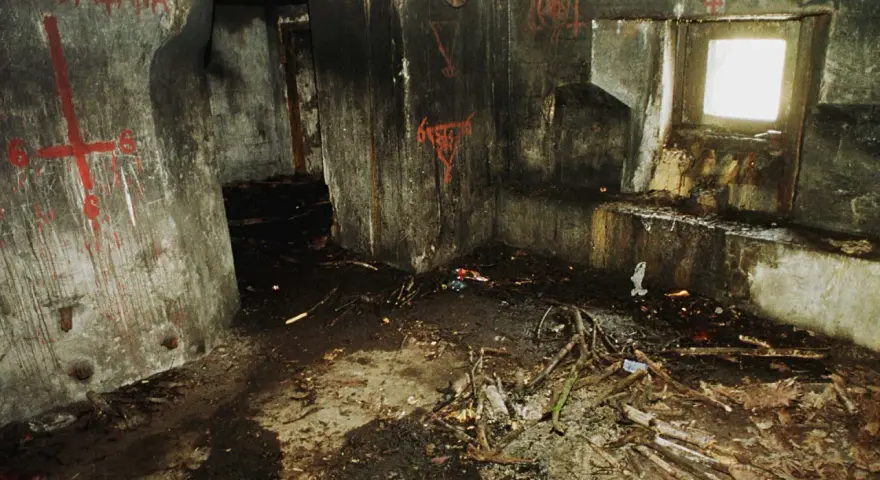Wnętrze bunkra 44, ściany pokryte graffiti, na podłodze gruz i gałęzie.