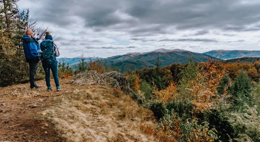 Dwóch turystów na szczycie, kamień i widok na góry. Czas przejścia przez jesienne Bieszczady.