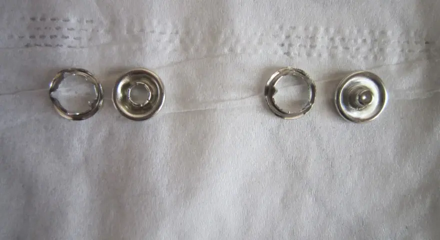 Quatre pièces de bouton pression métal argenté, prêtes à poser sans pince.