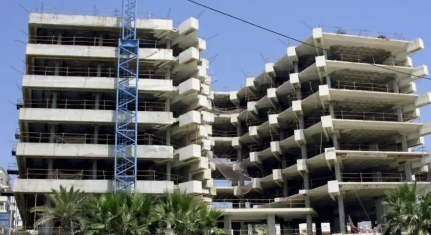 Edificio en construcción con grúa azul. La obra avanza lentamente, generando preocupación por sentencias de retraso en la entrega de vivienda de obra nueva.