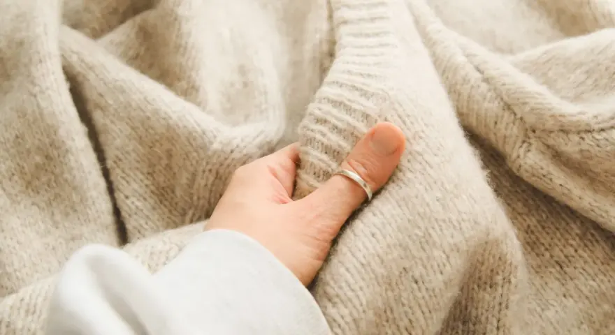 Mięciutki, beżowy, sfilcowany sweter z wełny, który otula dłoń.