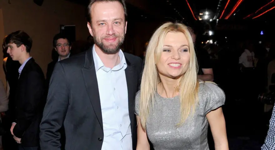 Julia Balsewicz w srebrnej sukience i mężczyzna w czarnym garniturze uśmiechają się do obiektywu.